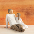 Willow Tree Father and Daughter, 5”h hand-painted resin figure of seated man dressed in neutral colors, legs outstretched, daughter in cream dress by his side, in front of sienna painting