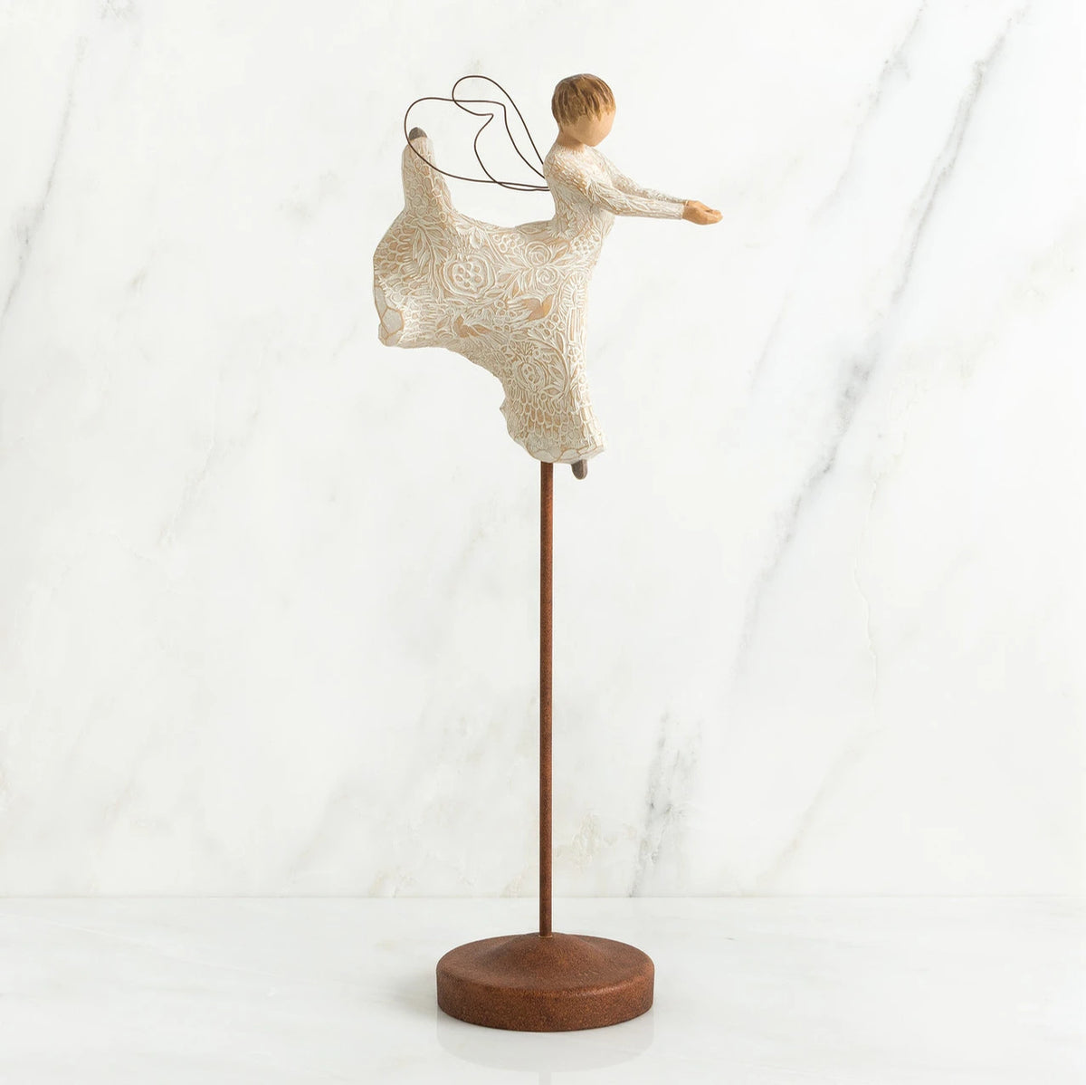 Faceless angel figurine wearing all white dress dancing on wooden pedestal stand