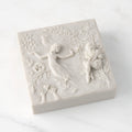 Closed white resin box; lid carved with figural and organic imagery