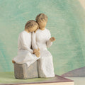 Willow Tree With my Grandmother, 5.5" hand-painted resin figure of older woman seated on gray bench, holding hands with young girl, both in cream dresses, in front of muted green painting