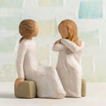 Willow Tree Heart and Soul, 4"h hand-painted resin figure of two women in cream dresses, seated on gray bench, facing each other, in front of pale green painting