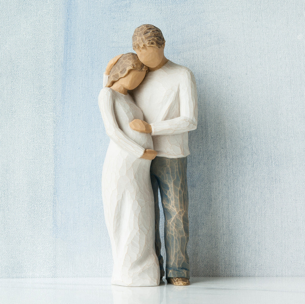 Willow Tree Home, 8.5”h hand-painted standing figure of man and pregnant woman embracing, both in neutral clothes, in front of grey blue painting