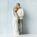 Willow Tree Home, 8.5”h hand-painted standing figure of man and pregnant woman embracing, both in neutral clothes, in front of grey blue painting