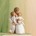 Willow Tree Quietly, 5”h hand-painted seated resin figure, one arm holding small toddler, other arm around standing older child, all in cream clothing, in front of green painting