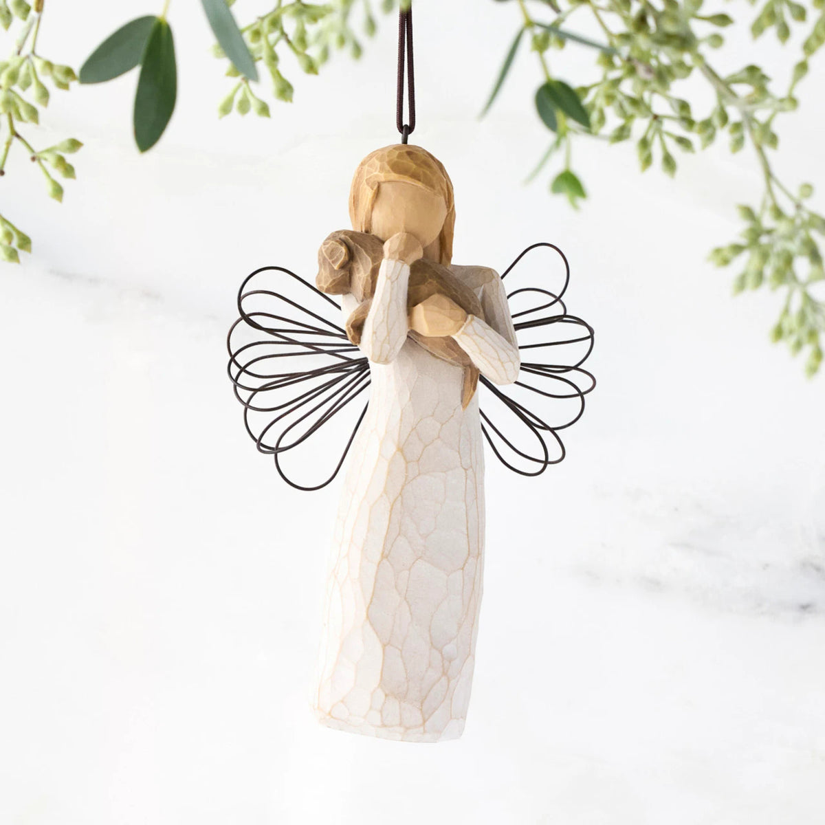 Female angel figure in cream dress with wire wings, holding brown dog in arms, ornament loop attached to head