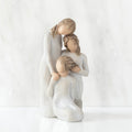 Front view, figurine of three females in cream dresses: one standing with arm around kneeling female, and holding hand of seated female
