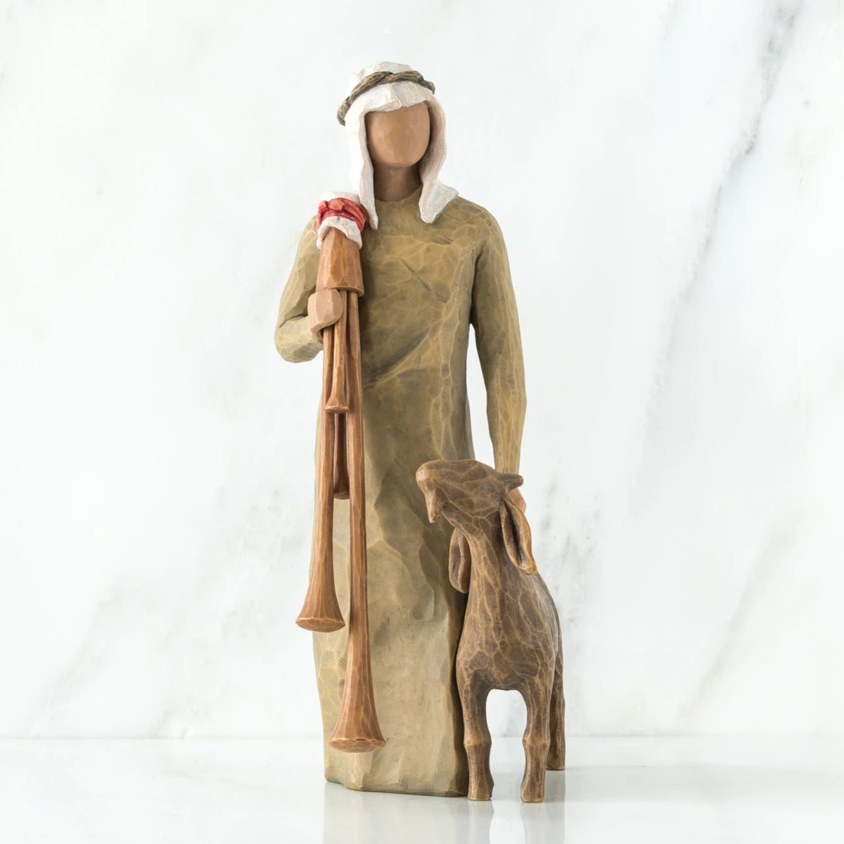 Wise man figurine standing in light brown attire with white headpiece, brown sheep at his feet