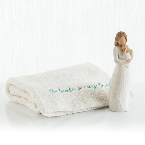 Brown haired woman figurine wearing white holding baby - next to white towel