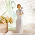 Willow Tree Grateful, 9”h hand-painted standing resin figure in cream dress, holding three wire flowers with long stems, on table with florals