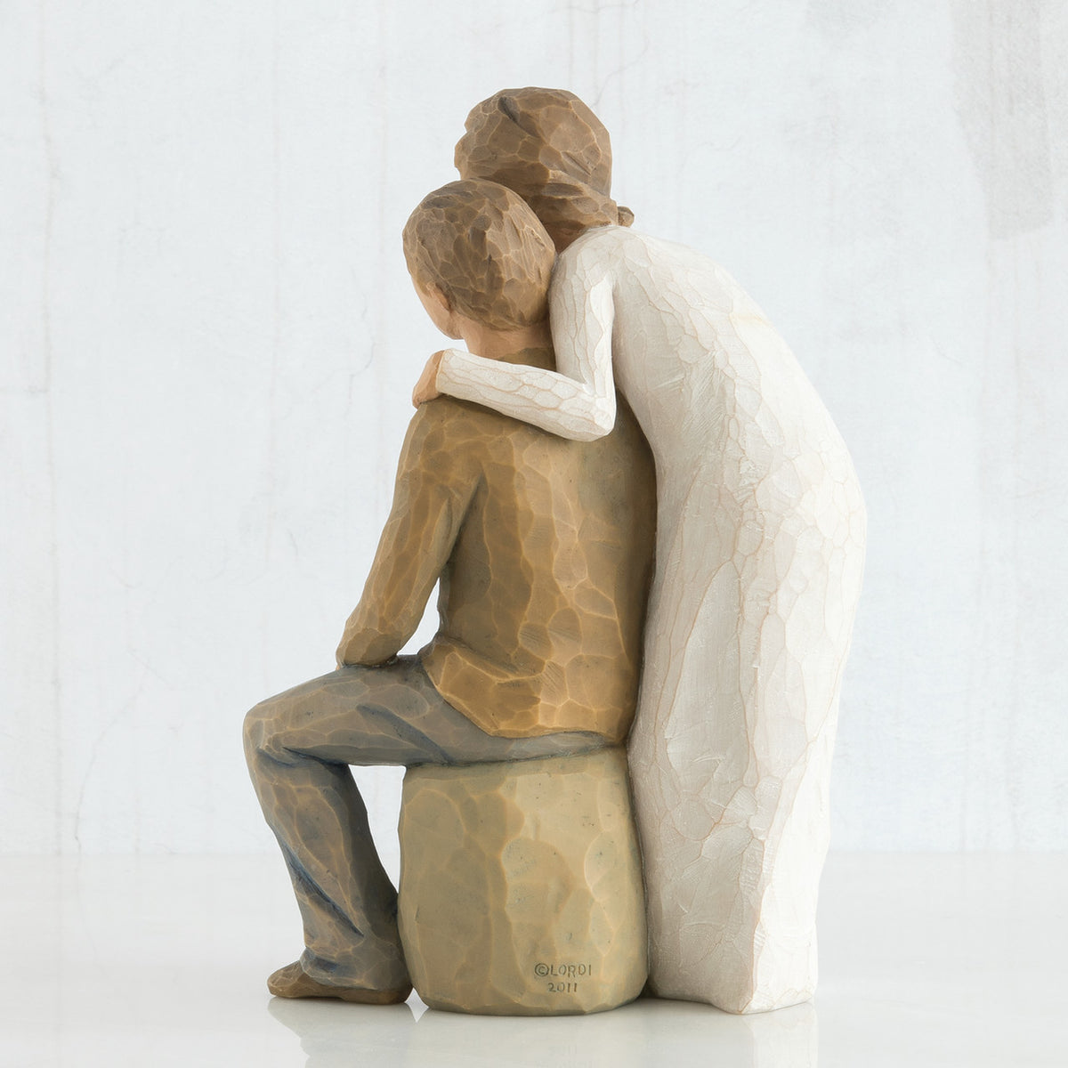 Back view - woman figurine in white dress hugging man figurine in brown shirt and blue jeans