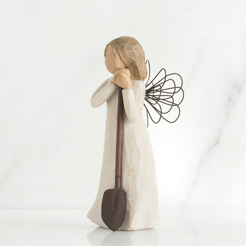 Young brunette girl figurine in white dress holding brown shovel
