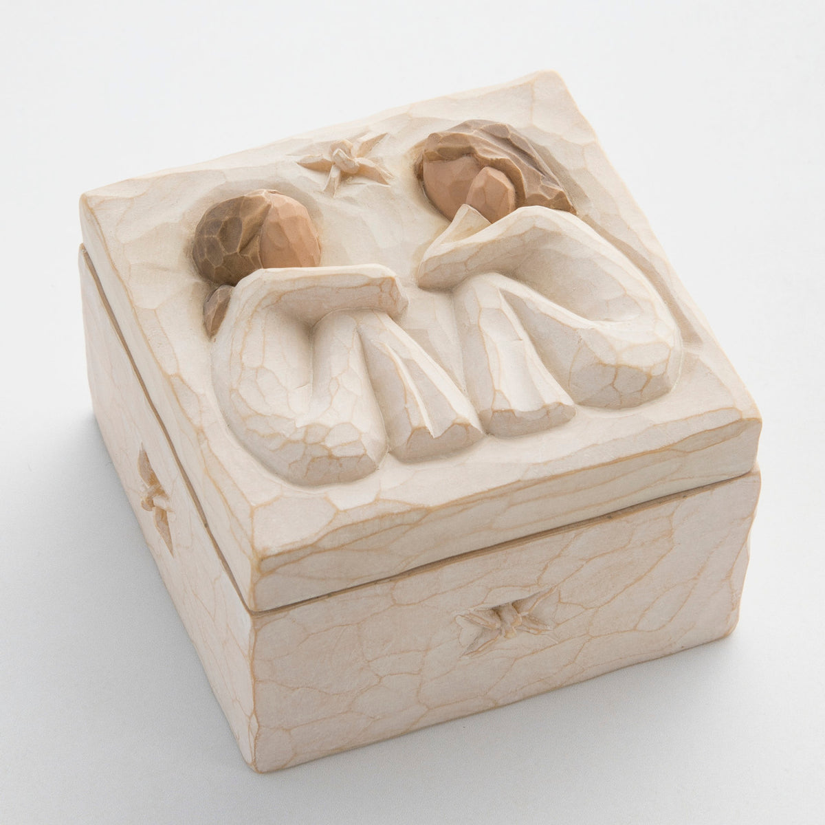 Close view of cream box with carved in image of two brunette girl figurines sitting down