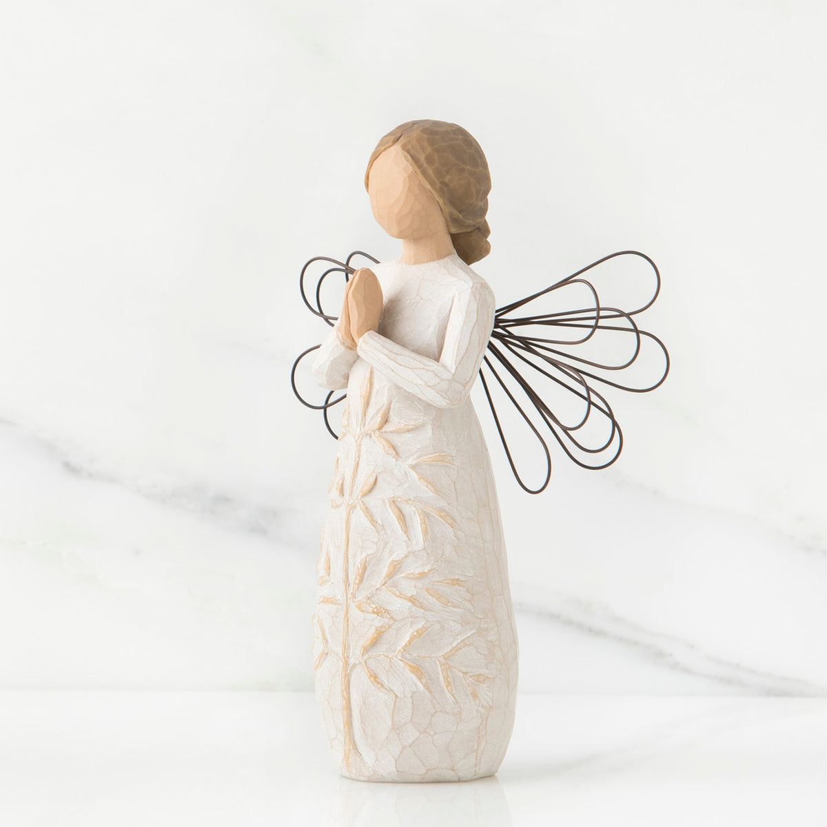 Side view of brunette angel figurine in white dress holding hands in prayer with black wire wings