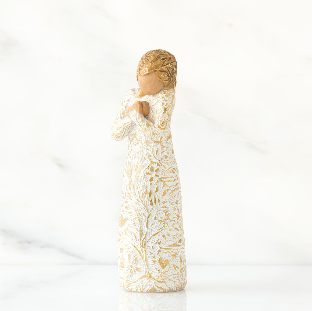 Gold haired woman in white/gold dress facing forward with arms to her chest