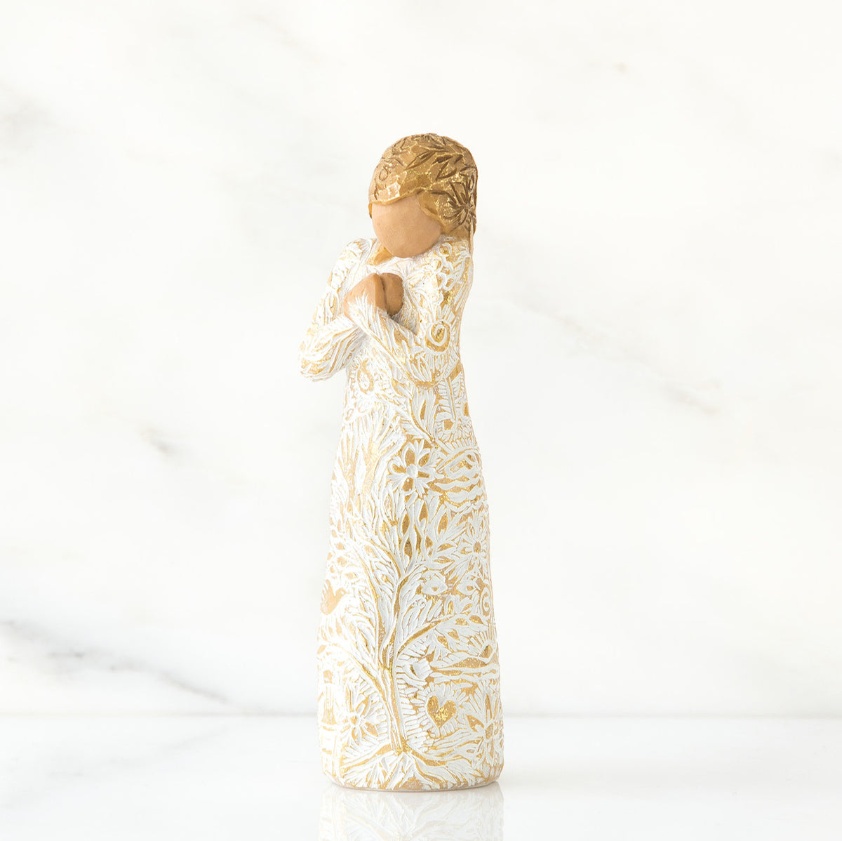 Gold haired woman in white/gold dress facing forward with arms to her chest