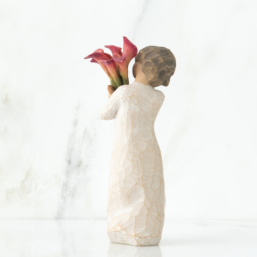 Back view of little girl with short brown hair holding a cluster of red calla lilies