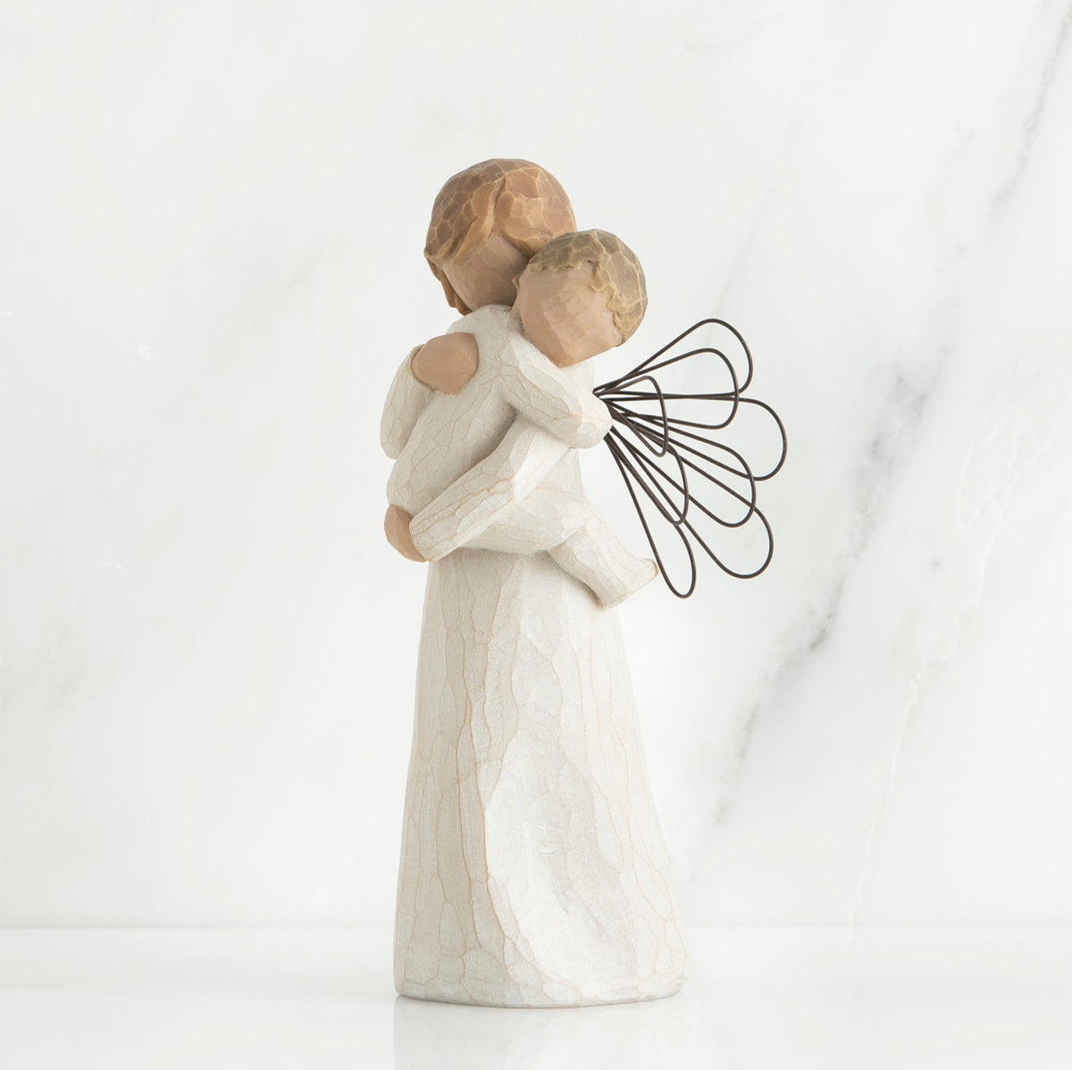 Angel figurine with black wire wings  in white holding baby in her arms