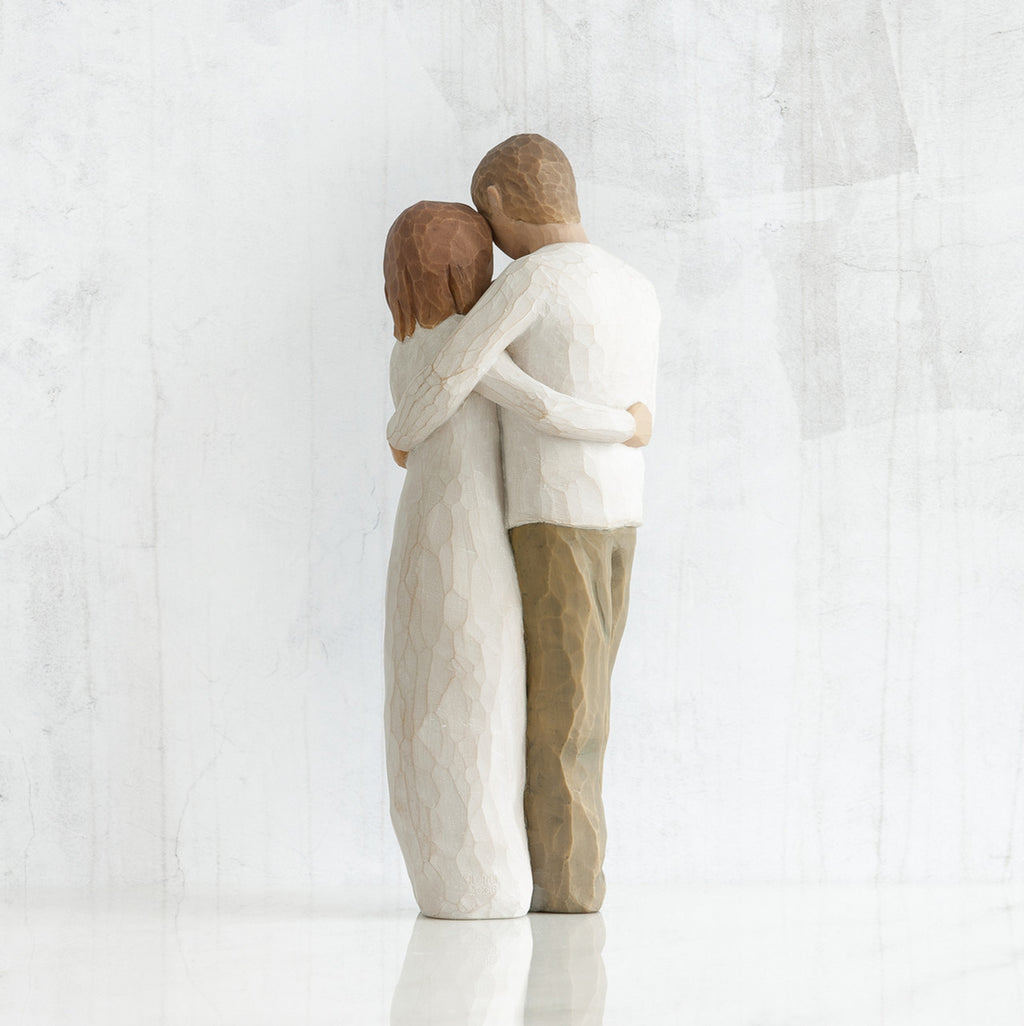 Man and woman figurines - back view - hugging another