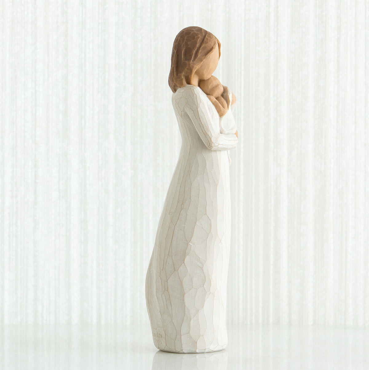 Side view of brunette woman figurine in white dress holding baby