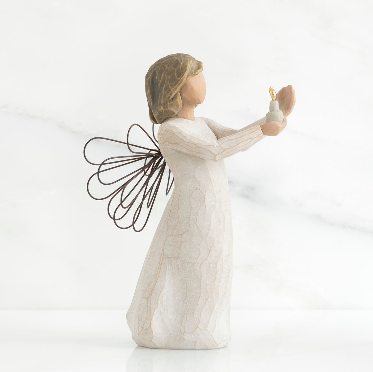 Side view of brunette girl figurine in white dress with brown wire wings holding up candle