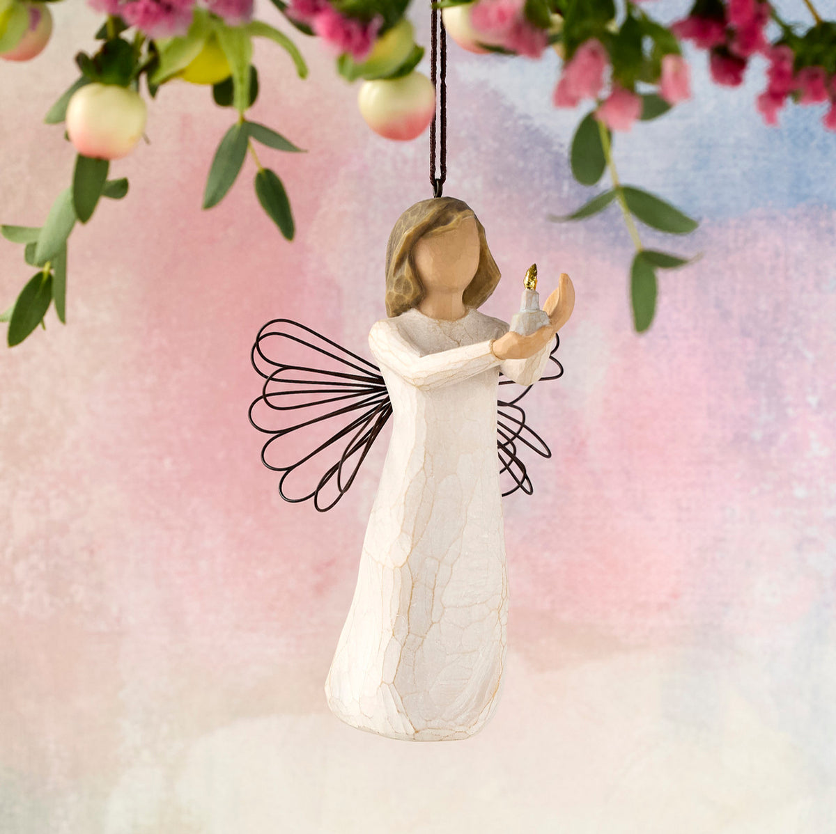 Willow Tree Angel of Hope Ornament, 4"h hand-painted resin figure in cream dress with wire wings, holding candle with gold-leaf flame in hands, brown elastic cord, hanging in front of dark yellow painting