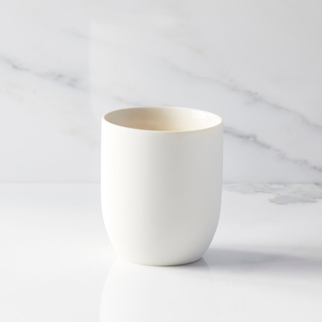 Back view of unglazed off-white tapered cylinder ceramic candle vessel