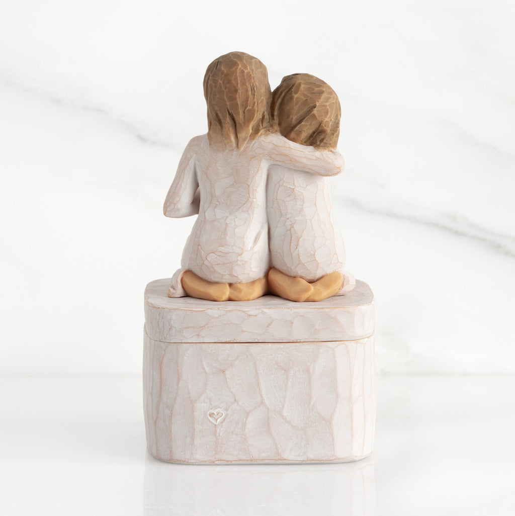 Back view showing heart carved into square resin box base: back view of two 3-D figures kneeling atop lid