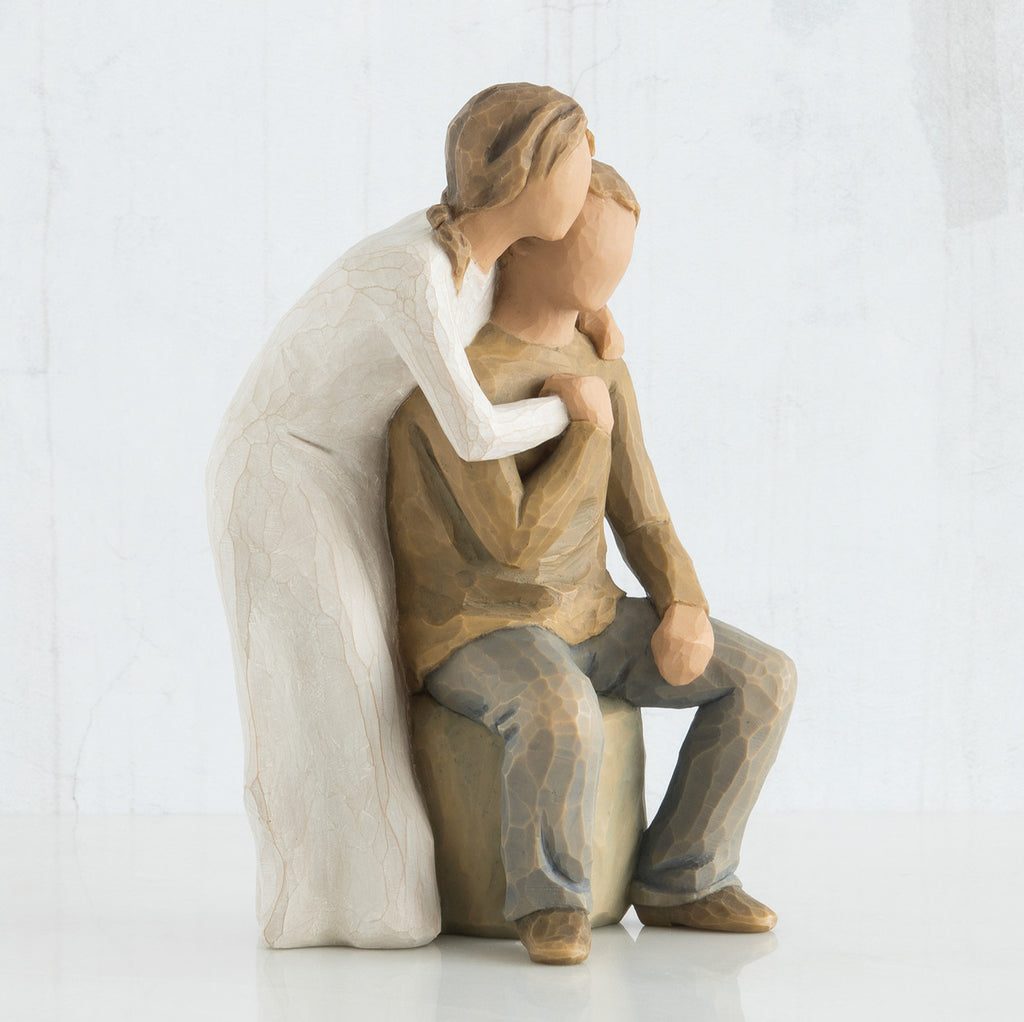 Close view of woman figurine in white dress with arms around man figurine in brown shirt
