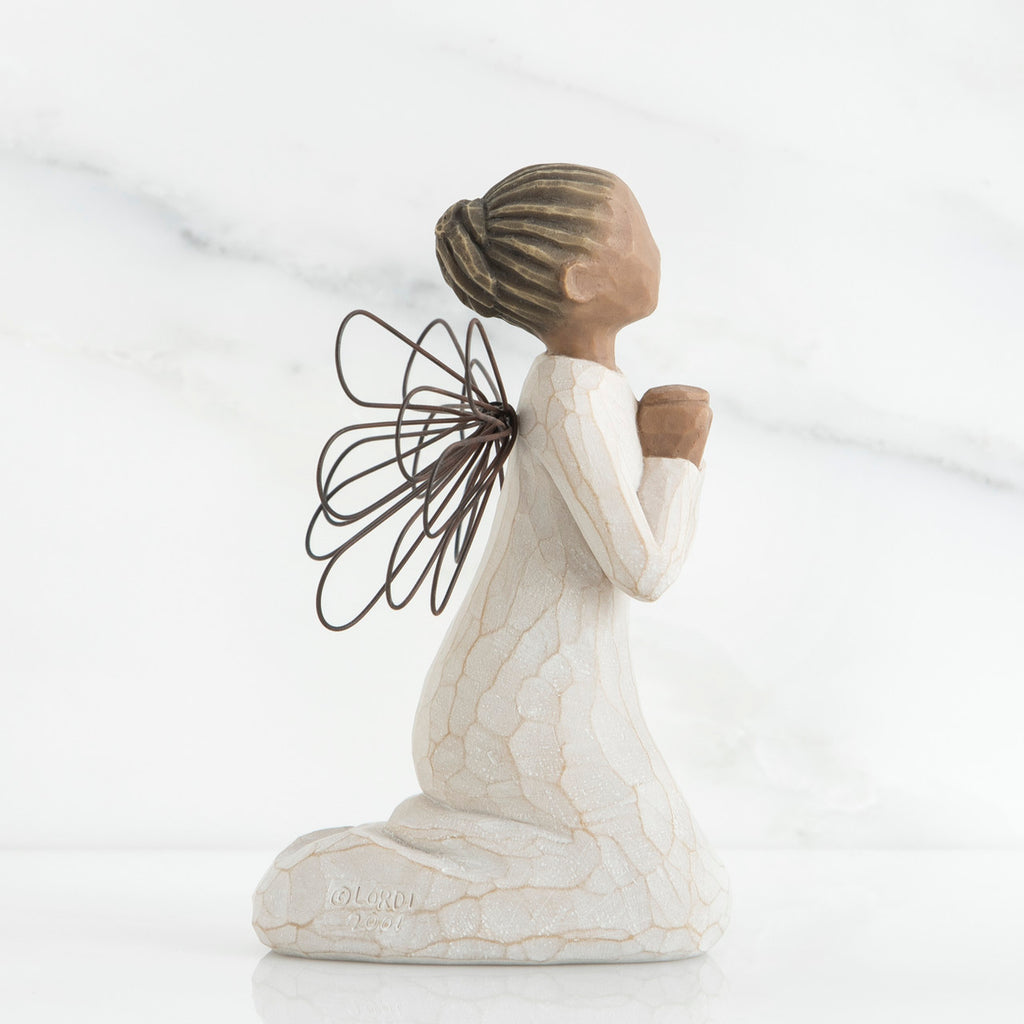 Side view of brunette angel figurine in white dress kneeling holding hands in prayer
