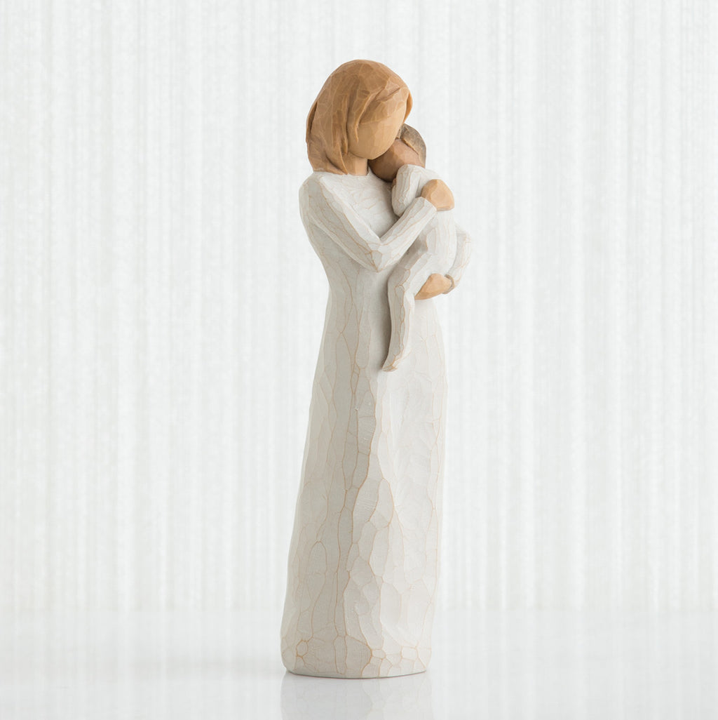 Front view of blonde woman figurine in white dress holding baby