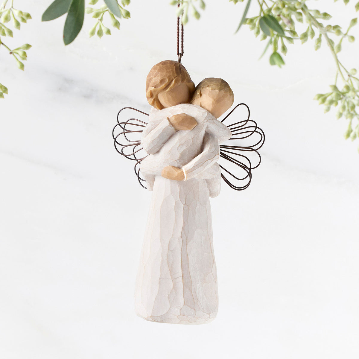 Figure of female in cream dress with wire wings, holding baby in cream onesie, with ornament loop on head