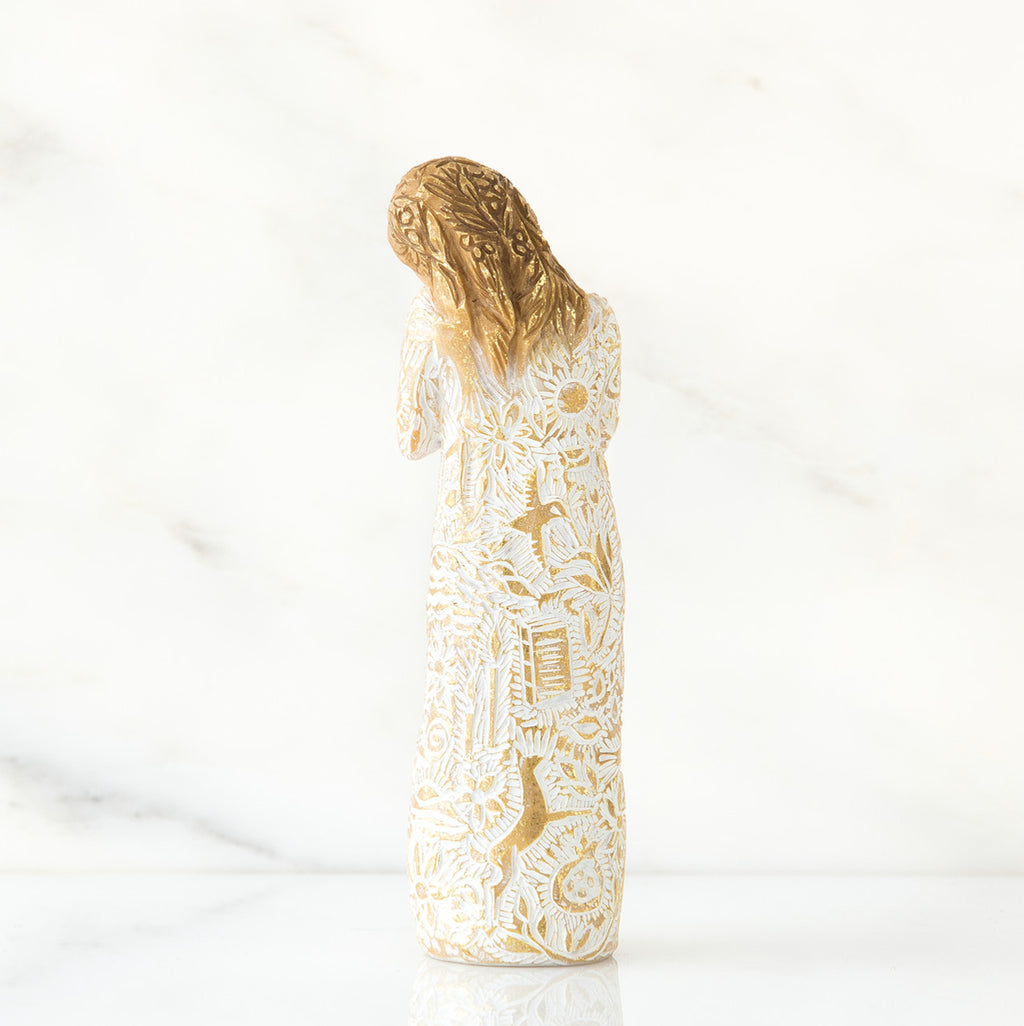 Gold haired woman figurine in white/gold dress facing away from the front