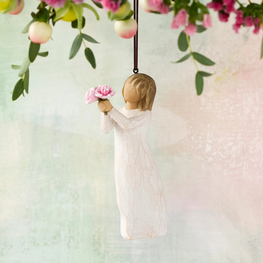 Willow Tree Thank You Ornament, 4”h hand-painted resin figure in cream dress, holding out bouquet of pink peonies, brown elastic cord, hanging in front of pastel painting