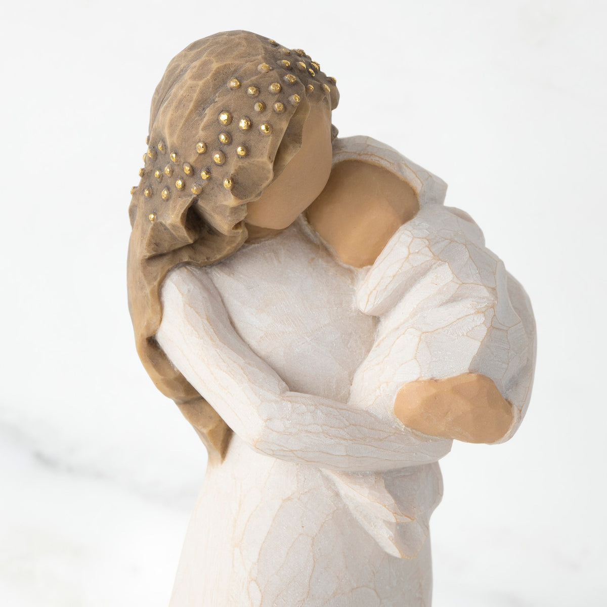 Close view of brunette woman figurine holding swaddled baby all in white