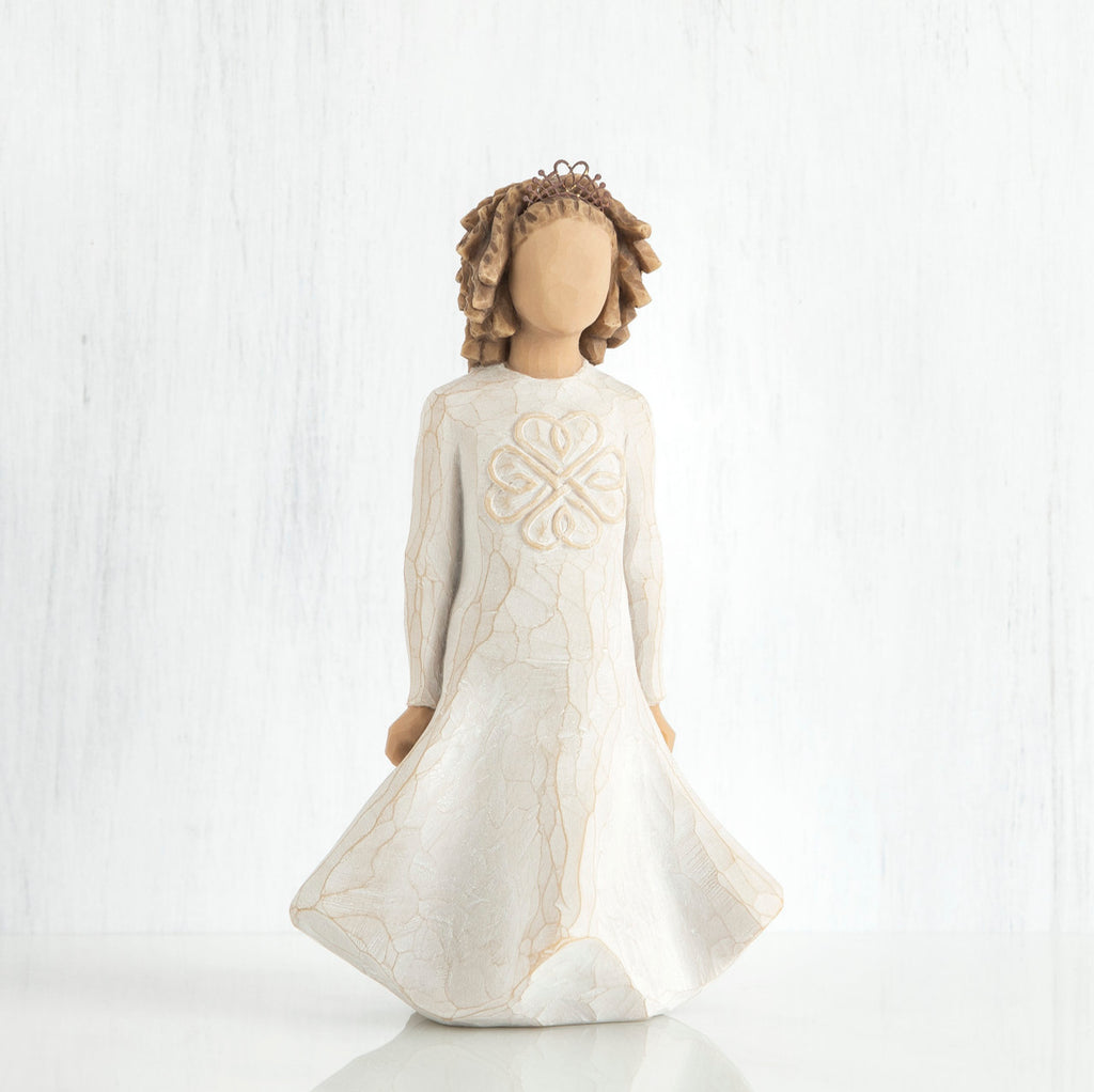 Faceless girl figurine with brown curly hair wearing white dress facing forward