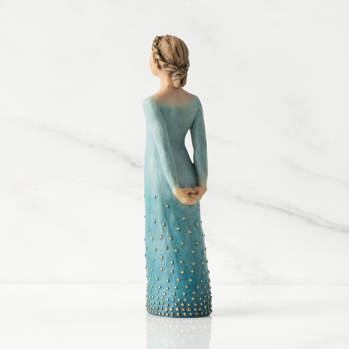 Facing left/back view: Lighter-skin figure, arms clasped behind back, hair and deep blue ombré garment dotted with gold leaf