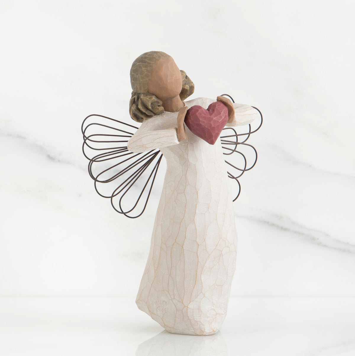 Faceless angel girl figurine wearing white dress and black wire wings holding maroon heart in her hands
