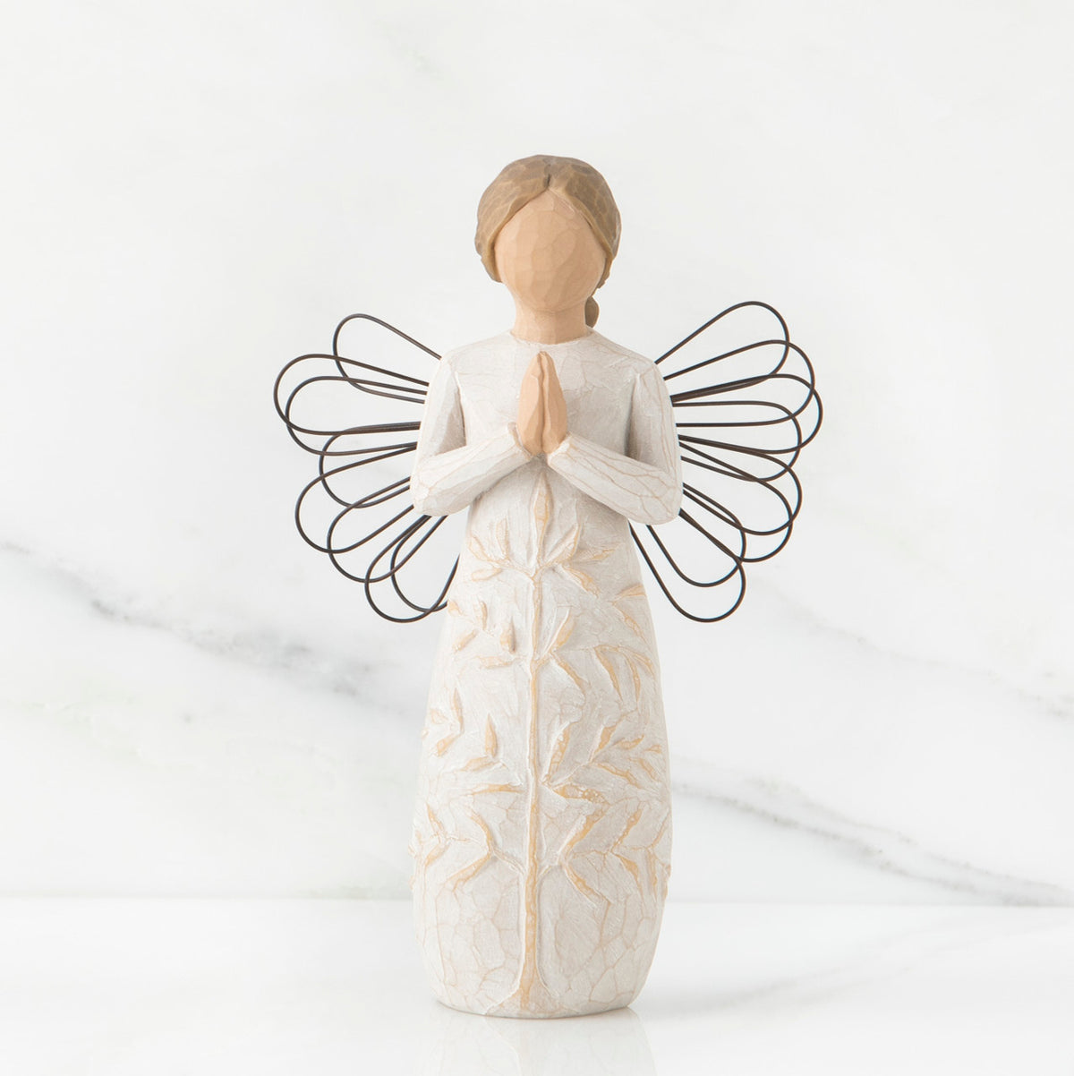 Faceless woman figurine in white dress with black wire angel wings - her hands are folded in prayer form