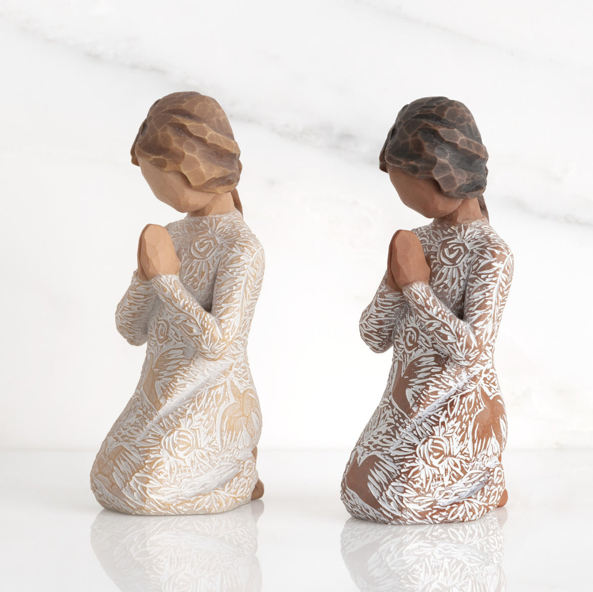 Lighter &amp; Darker skin Kneeling figures, hands in position of prayer or meditation in cream dress carved with icons of nature, lighter and darker skin versions