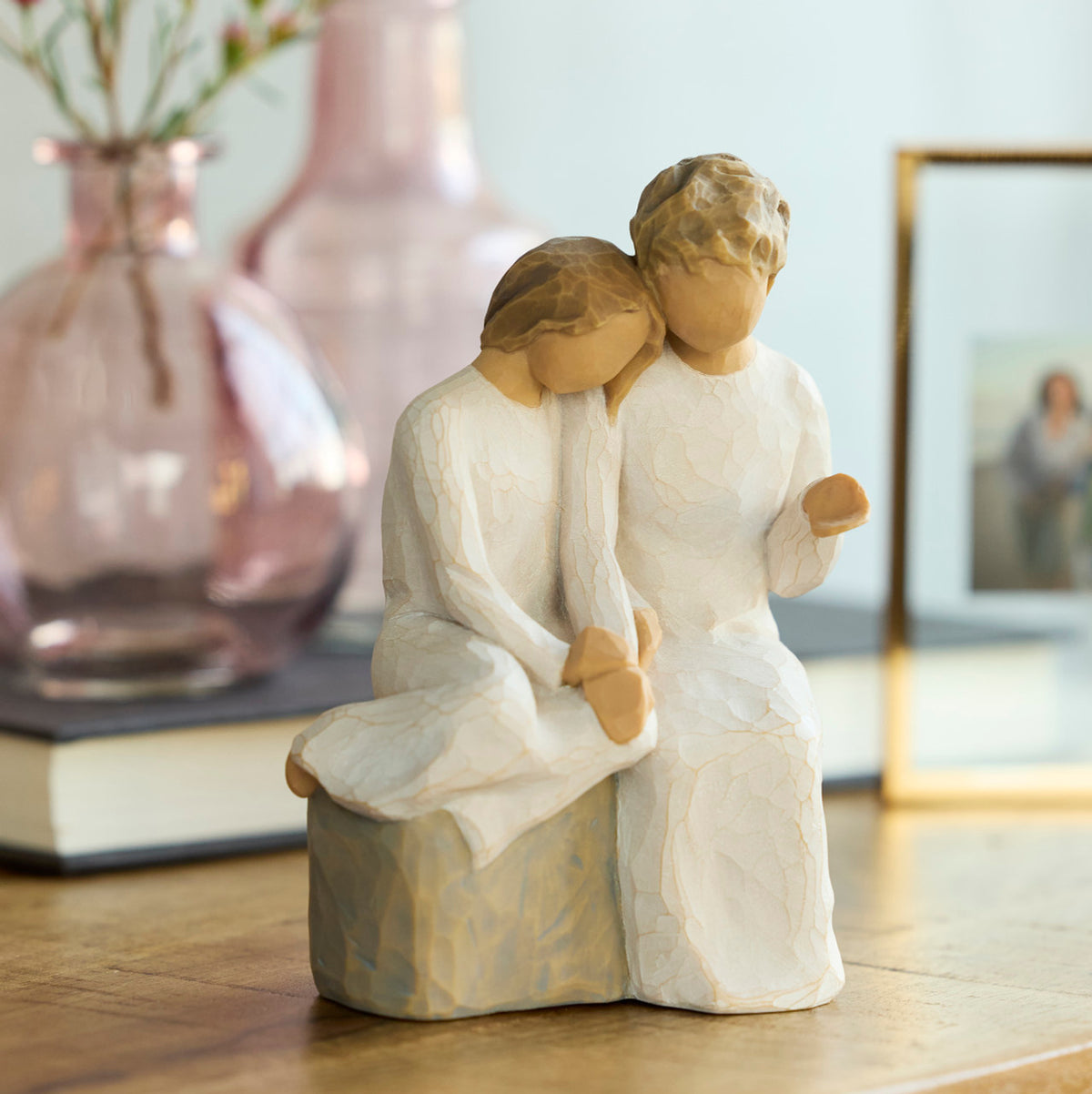 Willow Tree With my Grandmother, 5.5" hand-painted resin figure of older woman seated on gray bench, holding hands with young girl, both in cream dresses, on table with vase