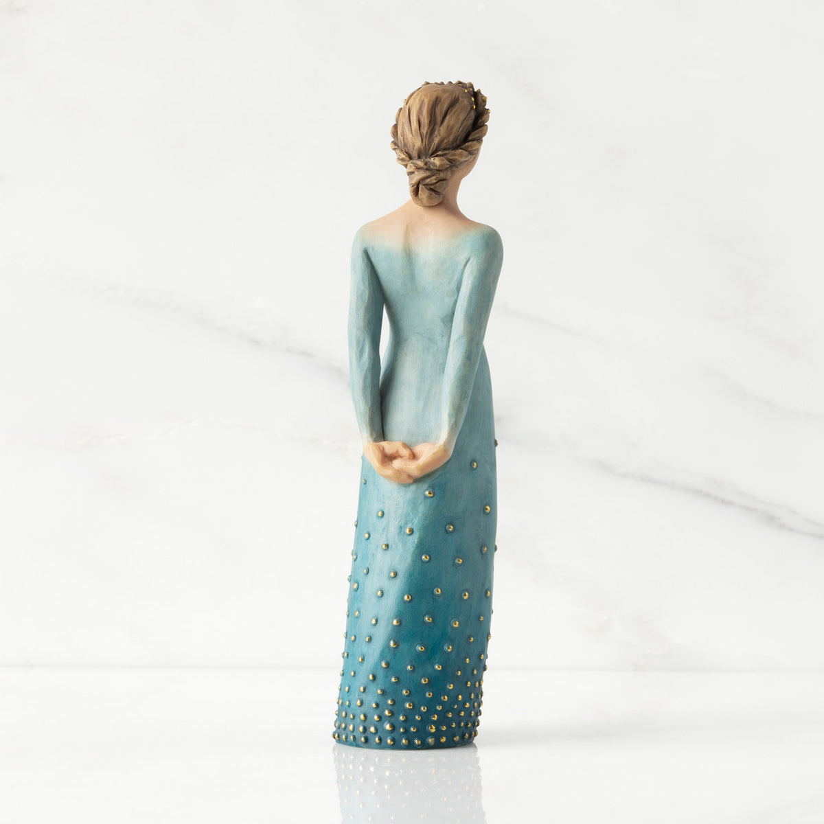 Facing back/right: Lighter-skin figure, arms clasped behind back, hair and deep blue ombré garment dotted with gold leaf