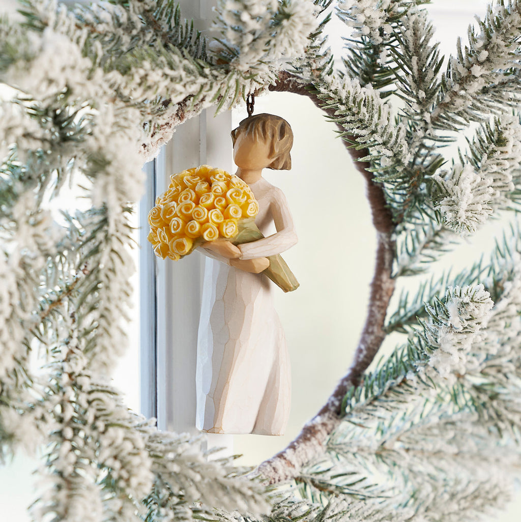 Willow Tree Good Cheer! Ornament, 4.5”h hand-painted resin figure in cream dress, holding bouquet of yellow roses, brown elastic cord, hanging inside white wreath