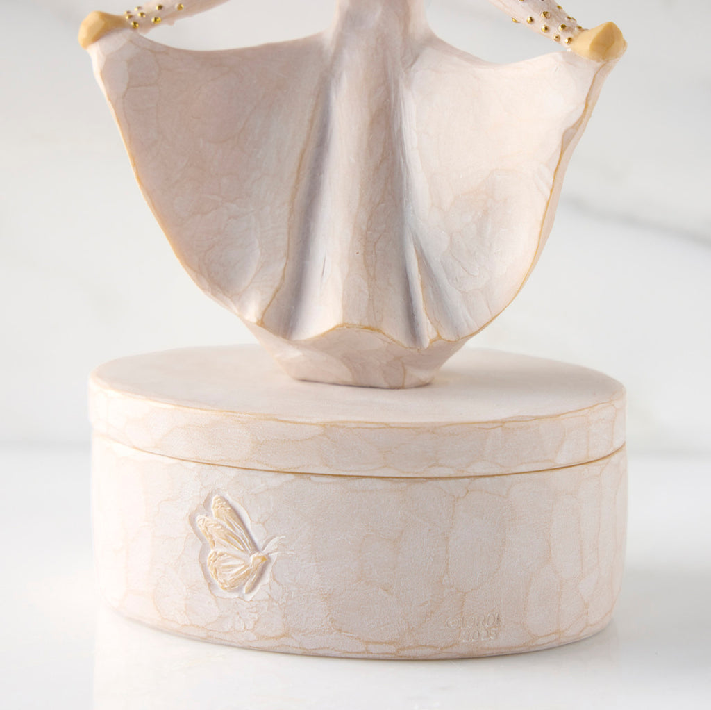 Detail view: back of oval resin box, showing carved butterfly detail on box base
