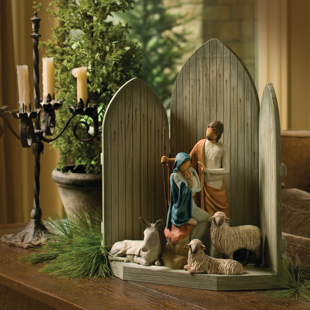 Side view of dark grey barn tri-fold on table with mary and joesph figurines in the center with two white sheep and donkey figurine under them
