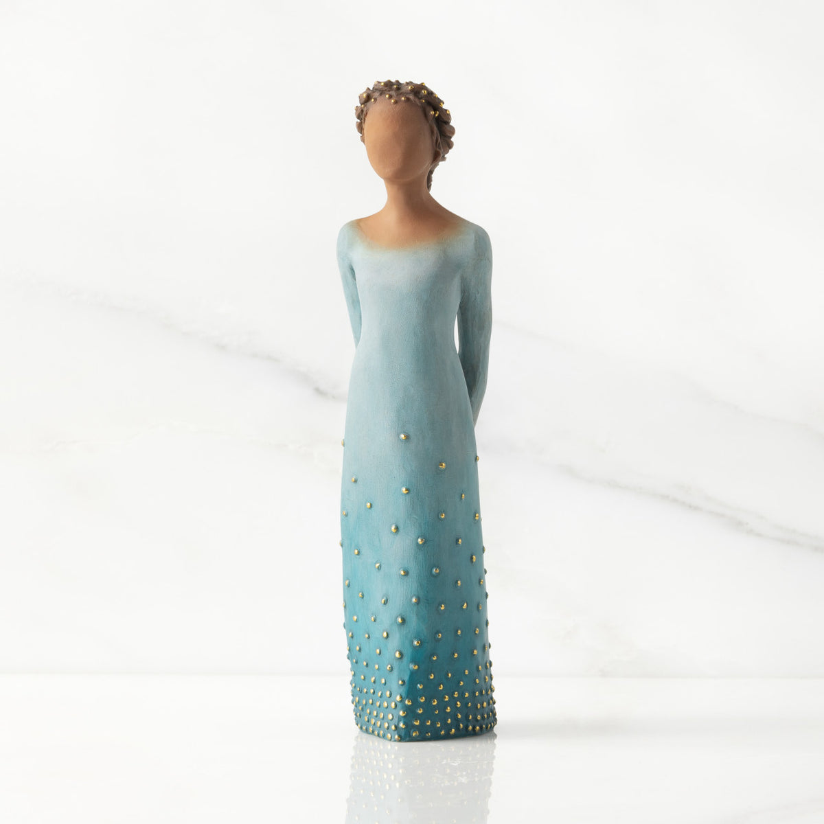 Facing front: Darker-skin figure, arms clasped behind back, hair and deep blue ombré garment dotted with gold leaf