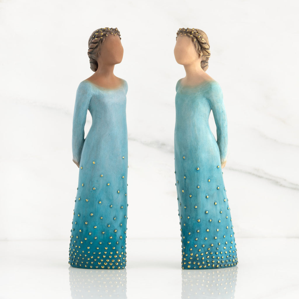 Front view of both lighter and darker-skin figures, arms clasped behind backs, hair and deep blue ombré garments dotted with gold leaf.