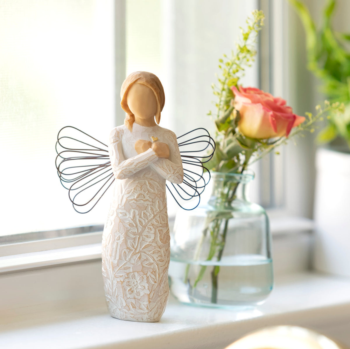 Willow Tree Remembrance, 5”h hand-painted standing resin angel figure in cream dress carved with symbols of nature, wire wings, crossed hands under small gold-leaf heart, on windowsill